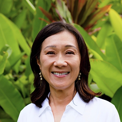 Dentist Angela Su Smiling In Front Of Greenery
