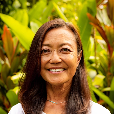 Dentist Arleen Regala Smiling In Front Of Greenery