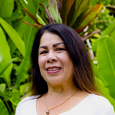 Front Desk Manager Chantel Smiling In Front Of Greenery