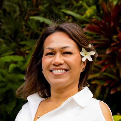Staff Member With Flower In Hair Smiling In Front Of Greenery